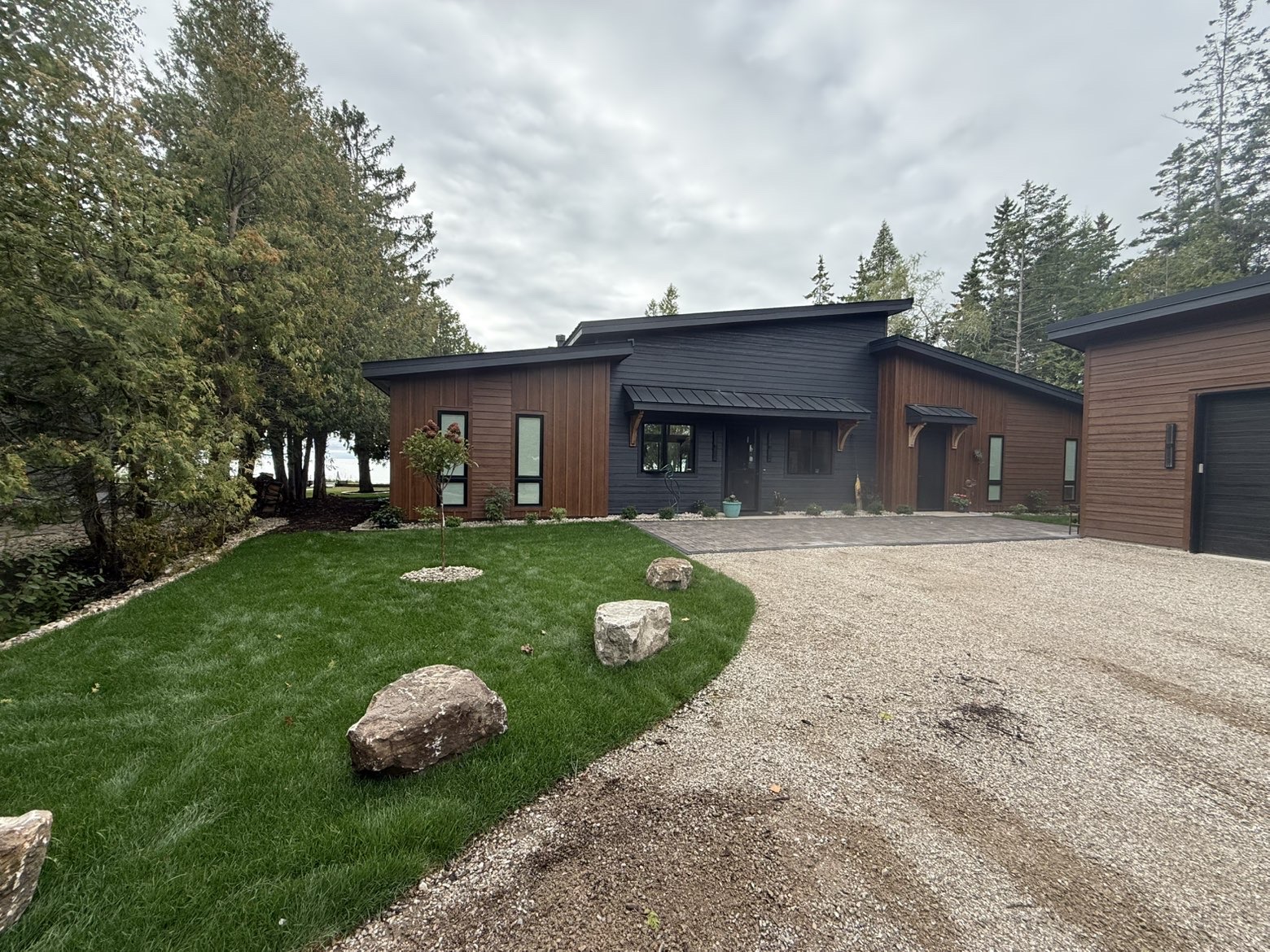 Finished front landscape with lawn, boulders, plantings and gravel drive