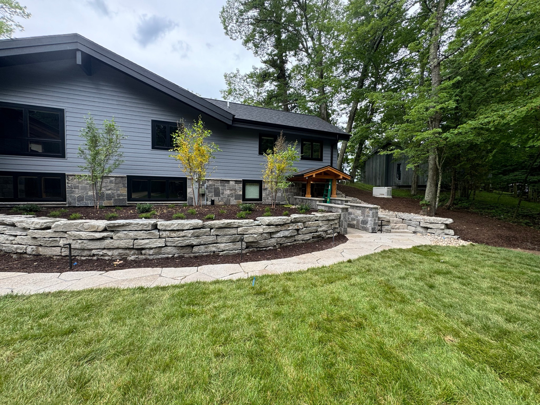 Natural stone wall, flagstone walkway, lawn and plantings